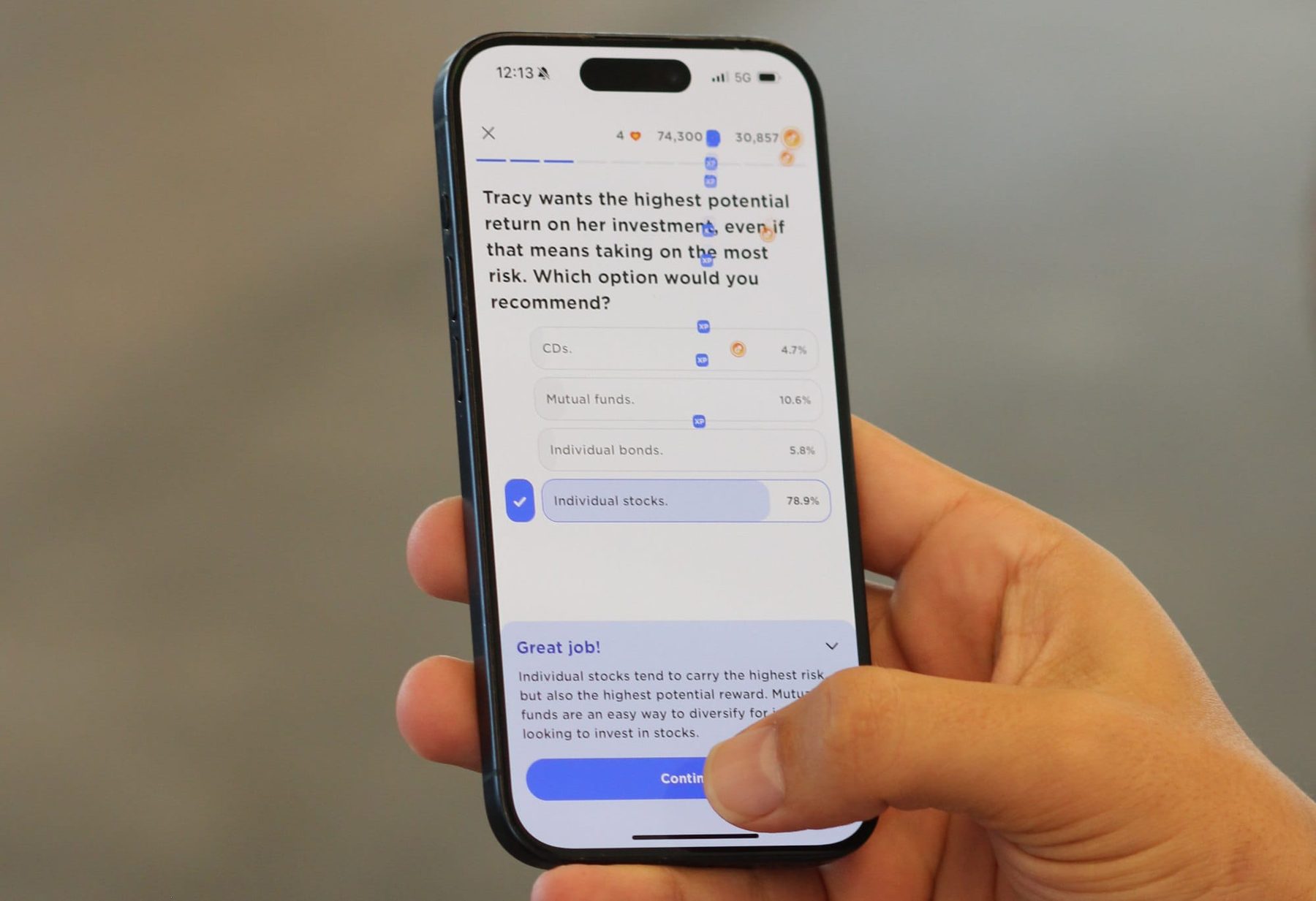 A hand holding a phone showing a Zogo lesson question about investment risk